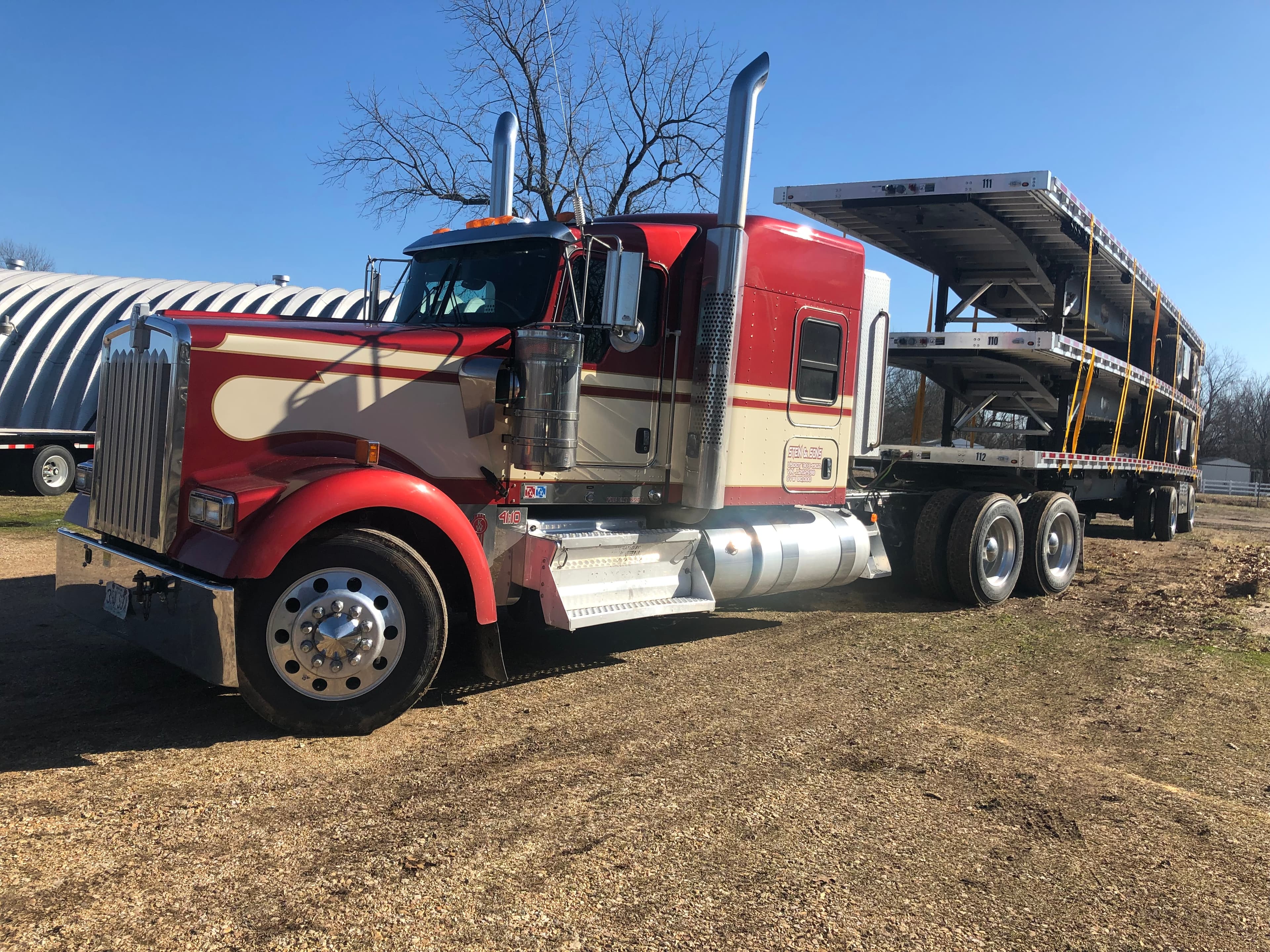 Stein & Sons Kenworth with company branding hauling stacked flatbed trailers