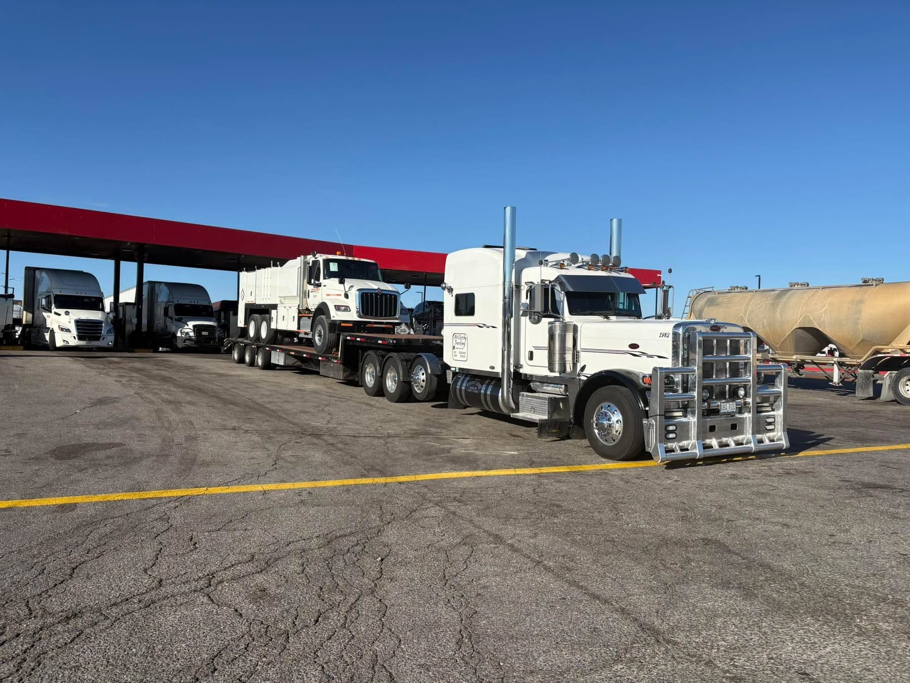 White Peterbilt flatbed hauling a utility truck