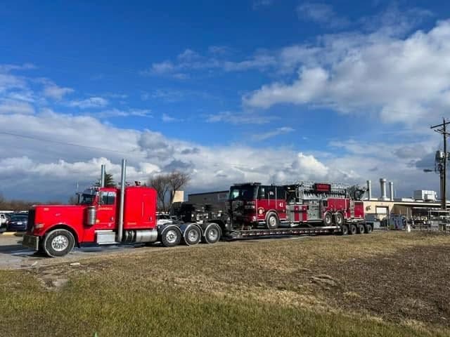 Red Kenworth lowboy with fire engine load