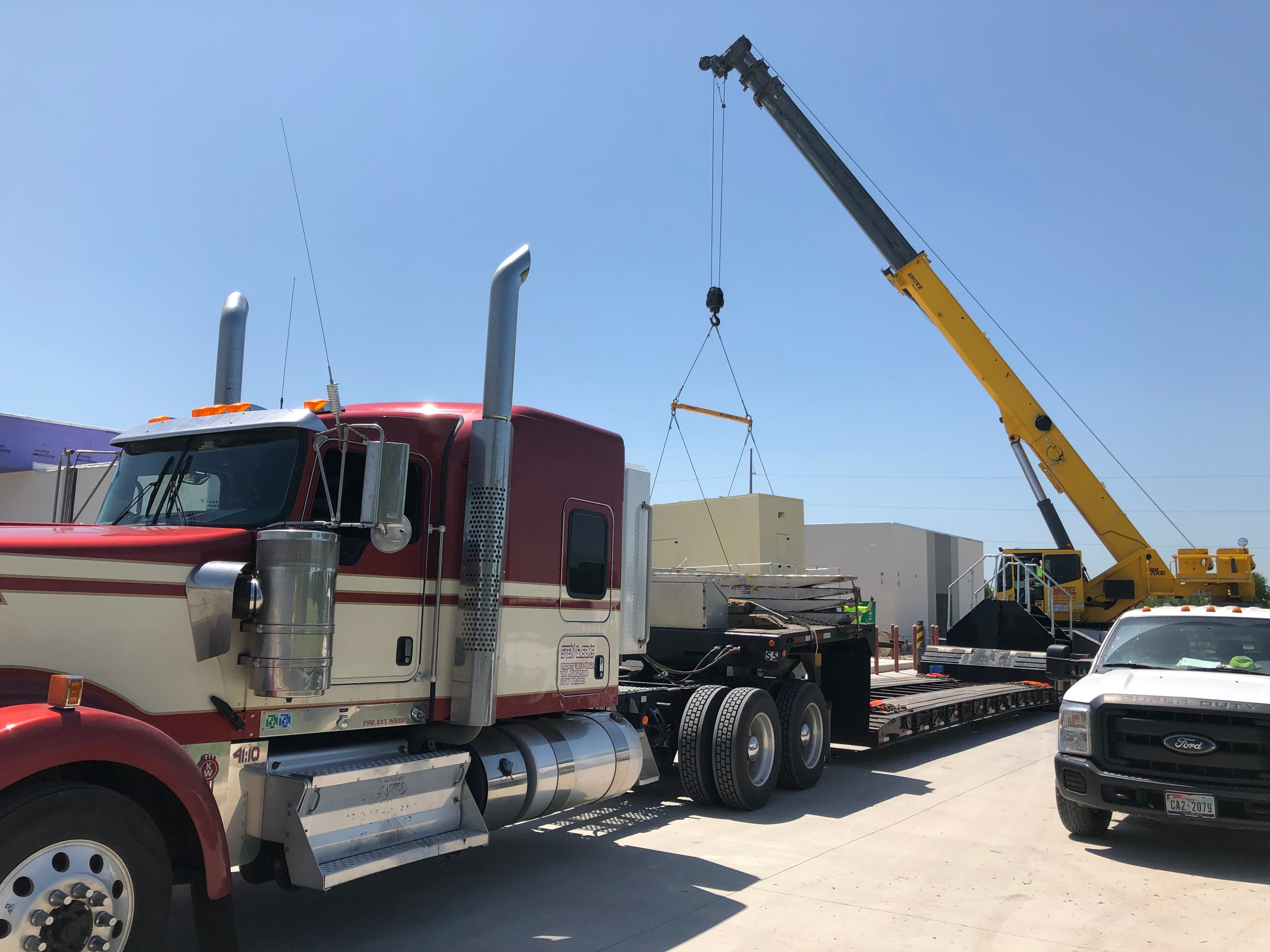 Crane loading industrial freight onto a Stein & Sons RGN trailer